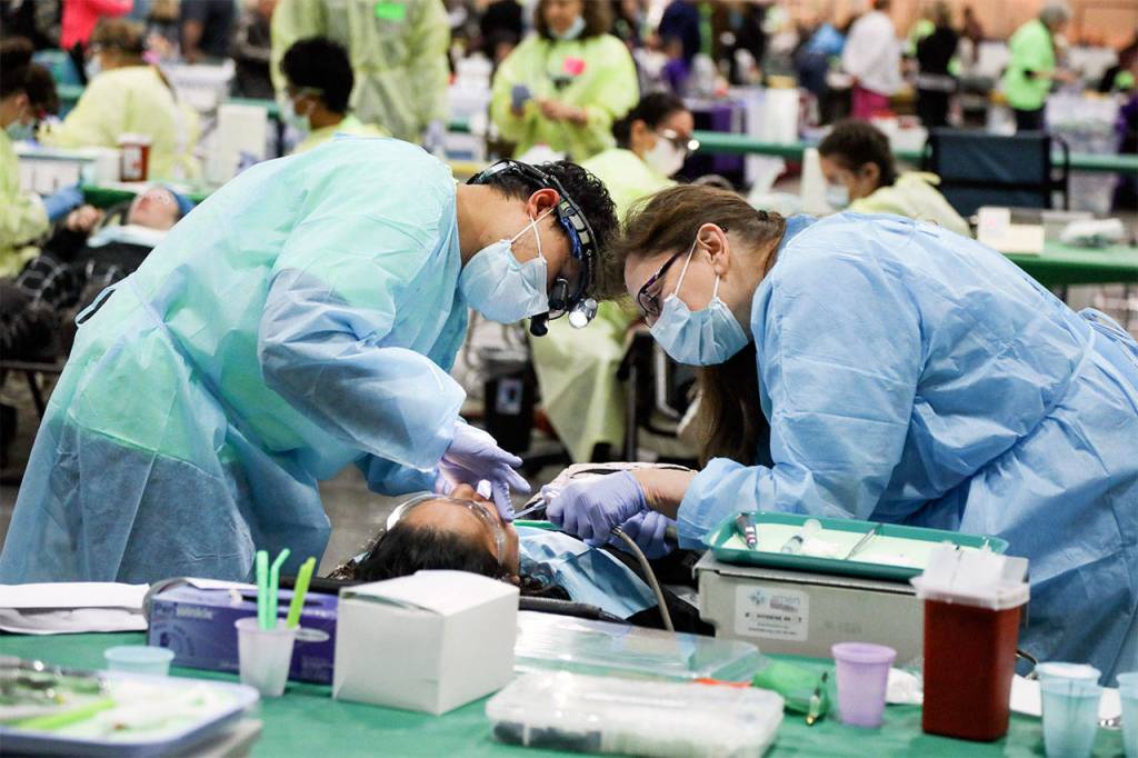 Dr. Michael Sacro and assistant Rosemary Garnick, both from Bellingham, provide dental services to a participant at the AMEN Clinic. (Photo by Heidi Baumgartner)