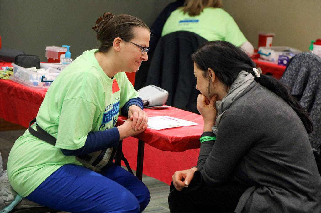 Anita Dorland, a nurse from Newcastle, prays with a participant at the AMEN Clinic. (Photo by Heidi Baumgartner)