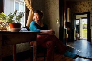 Andee Vaughan, 36, who loves old houses and rents this one, enjoys the play of sunlight Monday in the Swalwell Cottage. Said to be Everetts oldest standing house, it was completed in 1892, a year before the city was incorporated. (Dan Bates / The Herald)