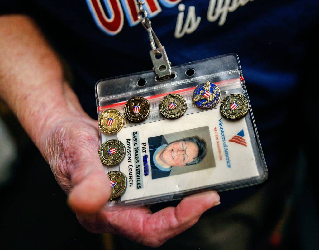 Volunteer Pat Reeve, 78, has seven pins on her VOA identification card for helping many hours. (Dan Bates / The Herald)