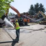 James Pearson hoses down roofing material pulled down while another excavator moves one of the ceiling beams as North Hill Resouces crews demolish the Hal Moe Pool on Monday in Snohomish. (Andy Bronson / The Herald)