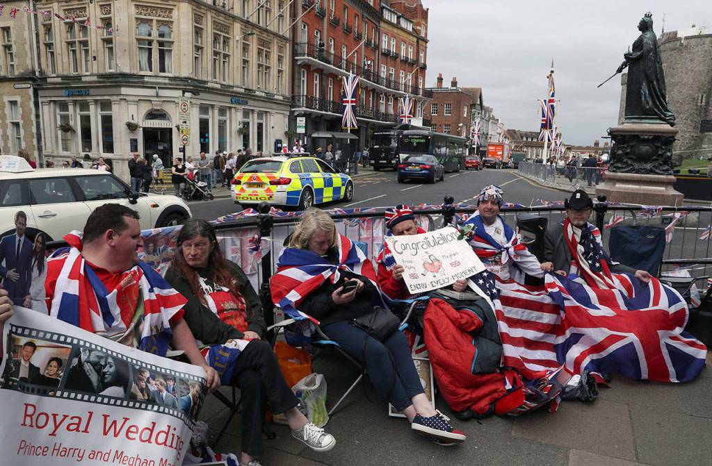 Royal fans John Loughry (second right) and Terry Hutt (center) show off their placards as TV and journalists film and interview them Wednesday just outside Windsor Castle in England. People lined up days in advance to view the procession. (Alastair Grant / Associated Press)