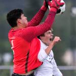 Redmonds Ricardo Escalante makes a save over Snohomishs Eli Esterly in a 3A state quarterfinal matchup on May 18, 2018, at Veterans Memorial Stadium in Snohomish. (Kevin Clark / The Herald)