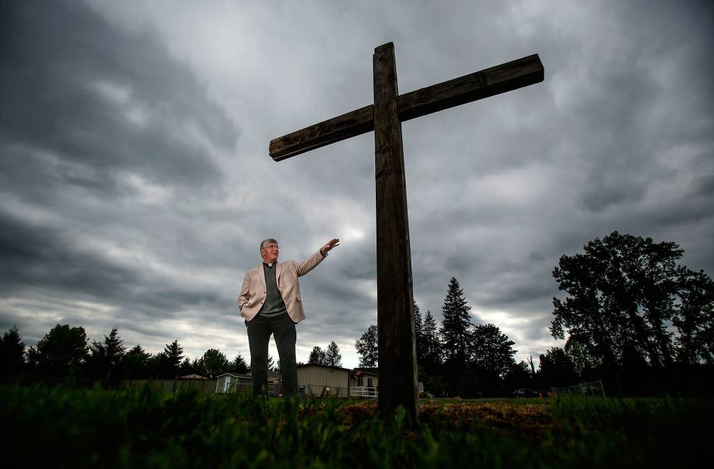 Standing on the marked ground where a new church will be built, Rev. Jay DeFolco of Holy Cross Catholic Church of Lake Stevens and Granite Falls talks about the parish. (Dan Bates / The Herald)