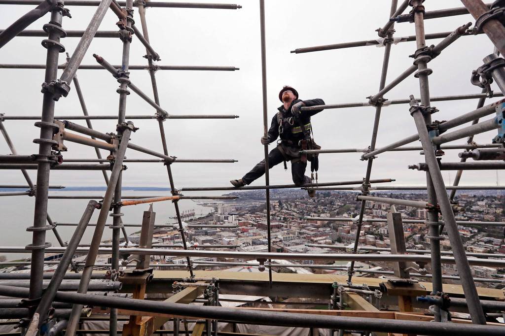 Josh Jagger climbs out on scaffolding as he builds it on the halo of the Space Needle in view of the Puget Sound and Queen Anne hill behind as work on a major remodel of the iconic observation tower continues Feb. 7 in Seattle. (AP Photo/Elaine Thompson, file)