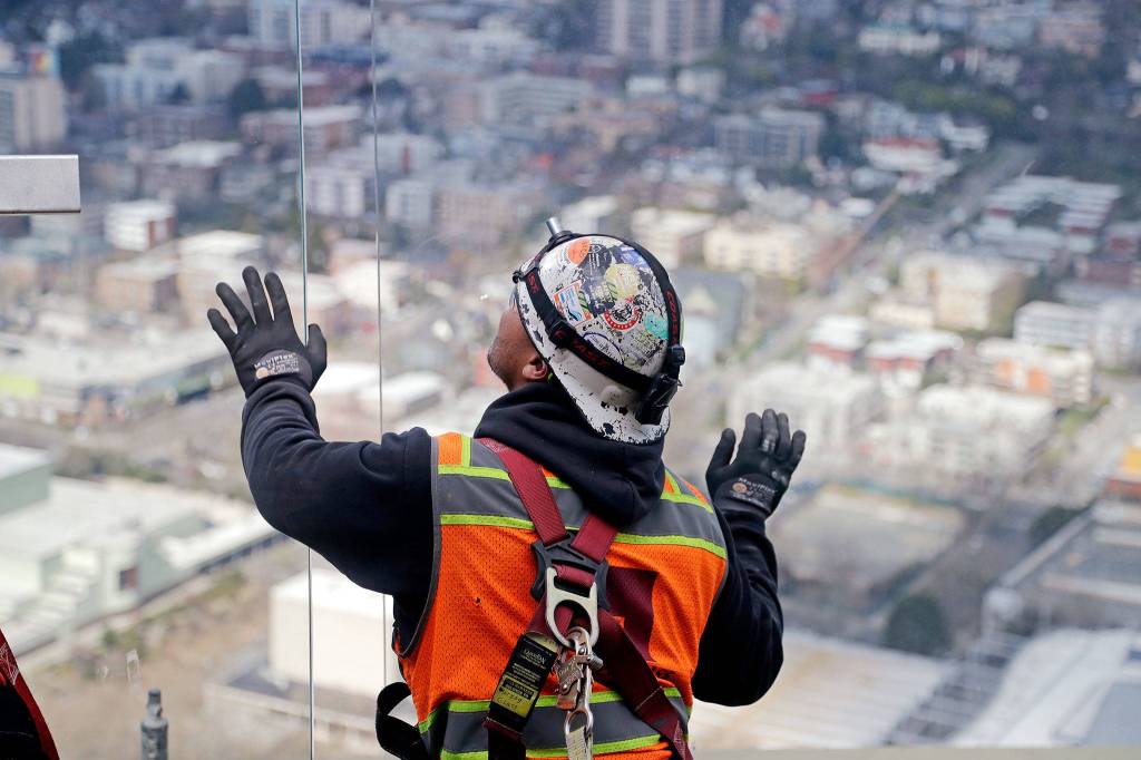 A glazer leans on one-ton glass panels as the one on the left is moved into position on the observation deck March 20 in Seattle. (AP Photo/Elaine Thompson, file)