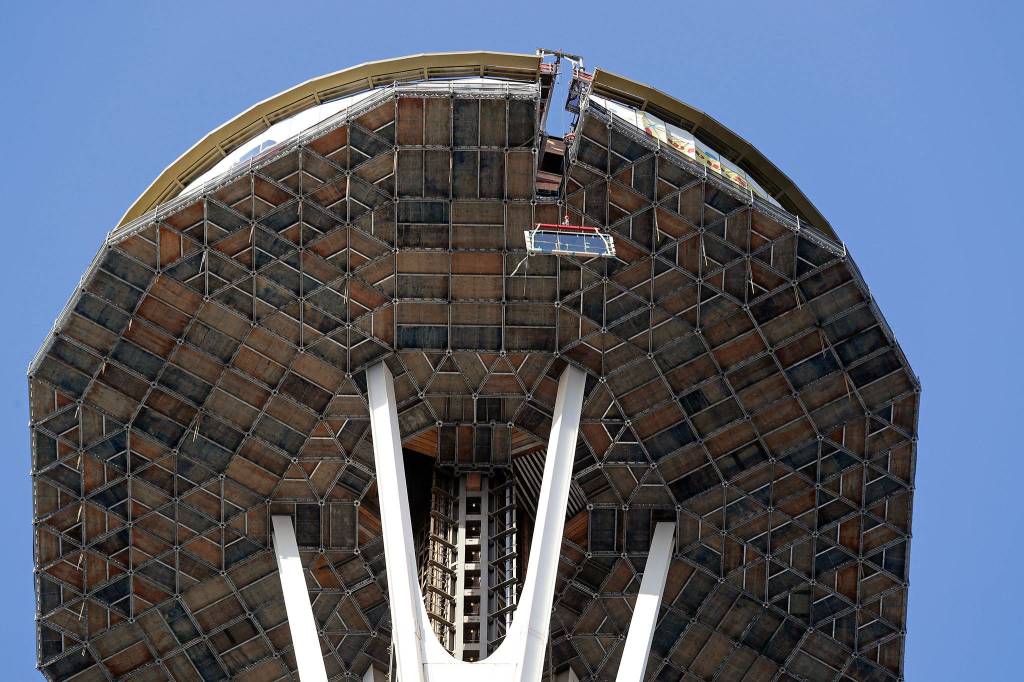 A gantry crane on the Space Needles observation deck lifts a one-ton glass panel through a narrow opening of scaffolding enclosing the upper structure on March 20 in Seattle. (AP Photo/Elaine Thompson, file)