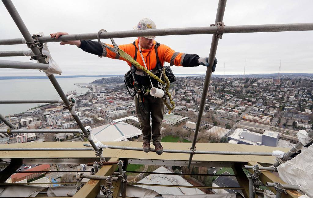 Jake Willis climbs out on scaffolding as he builds it on the halo of the Space Needle in view of the Puget Sound and Queen Anne hill behind as work on a major remodel of the iconic observation tower continued on Feb. 7 in Seattle. (AP Photo/Elaine Thompson, file)