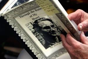 In her Snohomish-area home, Jean Bochan pages through the book she wrote and compiled chronicling the saga of her late husband. Paul Bochan, a native of Poland, was imprisoned by the Nazis during World War II, liberated from Dachau by American soldiers and later served in the U.S. Army during the Korean War. They were married 54 years before he died seven years ago. (Dan Bates / The Herald)