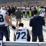 Former Seahawk Michael Bennett remains seated on the bench during the national anthem with teammate Justin Britt by his side before a game against Green Bay last season in Green Bay, Wis. (AP Photo/Jeffrey Phelps)