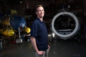 Josh Johnson, an intern for OceanGate, stands between two of the companys submersibles on Wednesday, May 23, 2018 in Everett, Wa. Johnson, who graduates from ORCA this spring, has been tasked with constructing a 3D printer for the company.(Andy Bronson / The Herald)