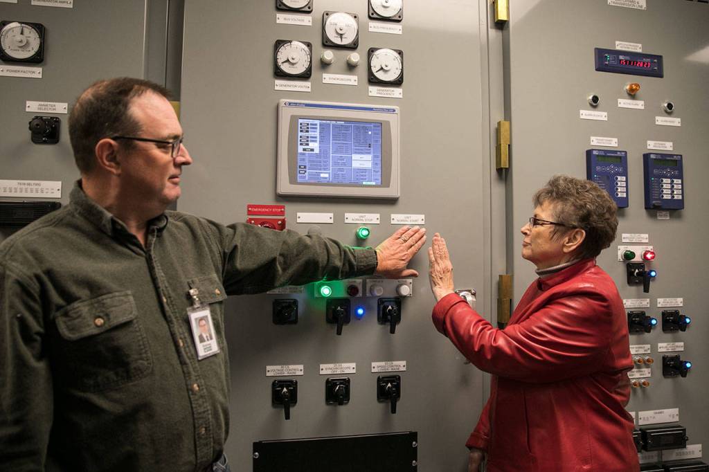 Sidney Logan (left) and Kathleen Vaughn, Snohomish PUD commissioners, start the Calligan Creek Hydro Project turbine. The project is located in King County. (Lizz Giordano / The Herald)