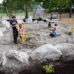 Carter King, 8, helps his sister, Rosie, 2, use an excavator in the sand pond as kids play at Logan Park on Monday in Lynnwood. (Andy Bronson / The Herald)