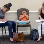 In this May 15 photo, Joan Herrera (center) sits and waits as his mother, Andrea Batista Garcia (left), and Marlene Gonzales (right) fill out job applications while attending the Great Northeast 2018 Job Fair at Capriottis in McAdoo, near Hazleton, Pennsylvania. (Ellen F. OConnell/Hazelton Standard-Speaker via AP, File)