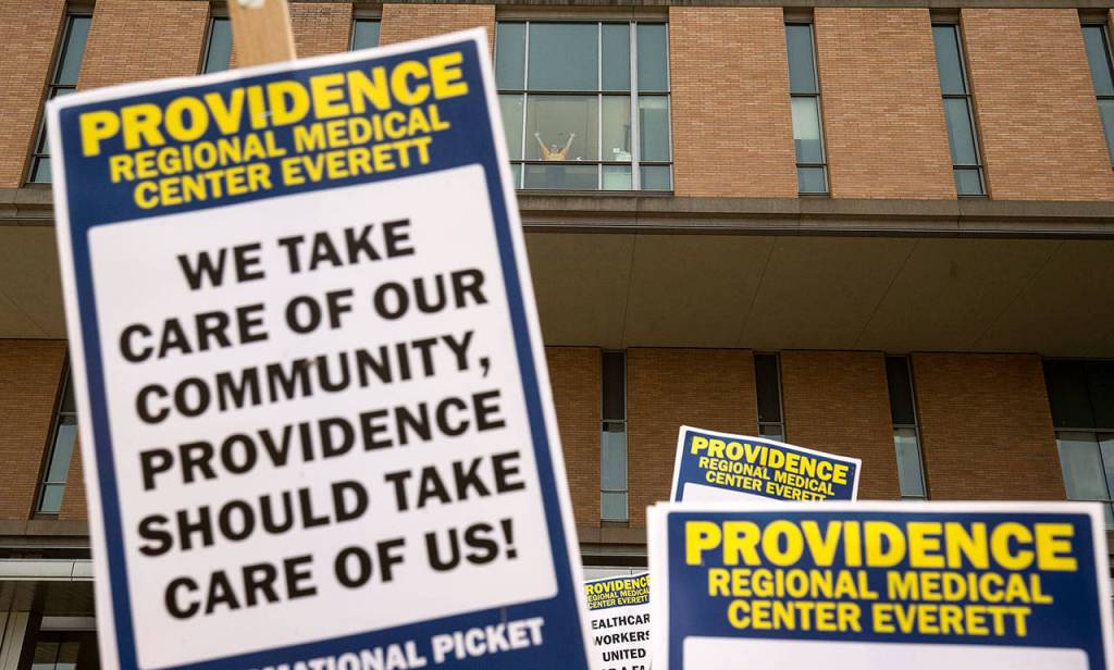 A supporter waves from a window as nurses with UFCW 21 and their supporters picket outside of Providence Regional Medical Center Everett on Wednesday. (Andy Bronson / The Herald)