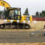 Tom Browne rakes the sand in preparation for the groundbreaking ceremony Saturday morning at the site of the new Everett Family YMCA. (Kevin Clark / The Herald)