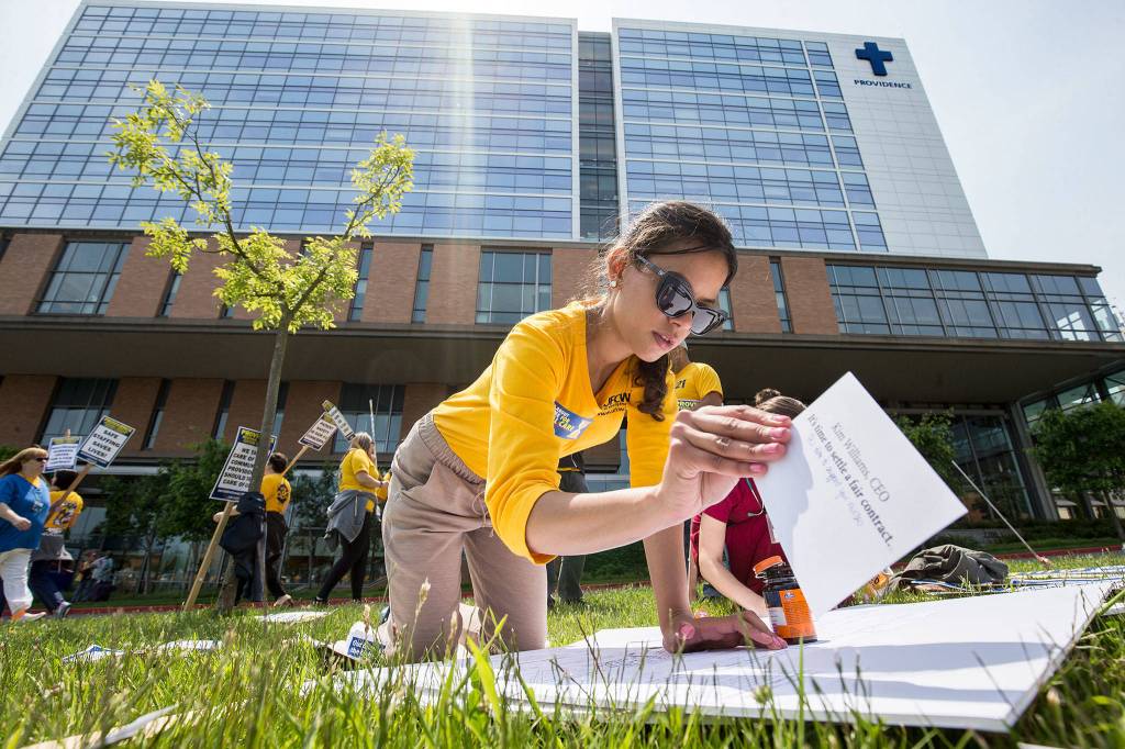 UCFW organizer Graciela Nunez affixes cards address to various administrators on a board as nurses with UFCW 21 and their supporters picket at Providence Regional Medical Center Everett on June 6, 2018 in Everett. (Andy Bronson / The Herald)