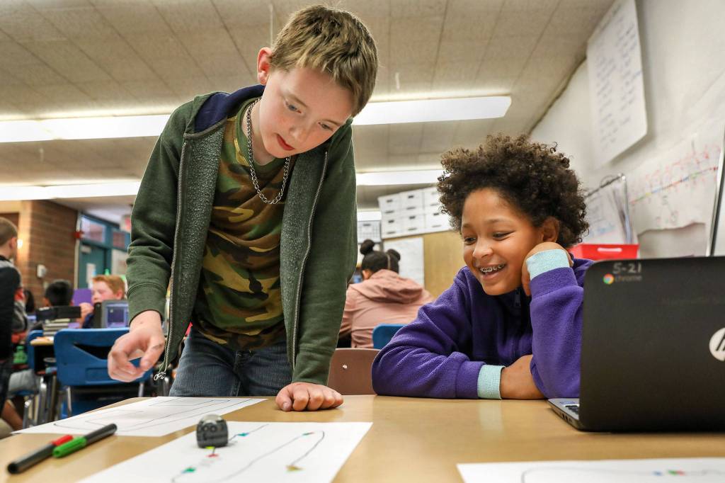 Gavin Dyche (left) and Ayla Martin, third grade students at Pinewood Elementary School in Marysville, learn to direct a robot though code using a Chromebook on May 15, 2018. (Lizz Giordano / The Herald)