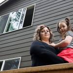 Kate Hitter holds her youngest daughter, Scarlett under a third story window at their Lake Stevens home on April 1, 2017. on Tuesday, May 1, 2018 in Lake Stevens, Wa. While moving in, Scarlett fell through a screened window and landed on the concrete patio 30 feet below. (Andy Bronson / The Herald)