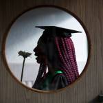 Seen through a door window, Marshawna Green smells a flower as she waits for the Sequoia High School graduation ceremony at the Everett Civic Auditorium on Thursday. (Andy Bronson / The Herald)