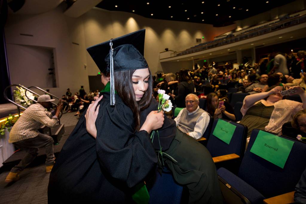 Caireanna Mills and other seniors walk out to their seats and hug audience members during the Sequoia High School graduation ceremony at the Everett Civic Auditorium on Thursday. (Andy Bronson / The Herald)
