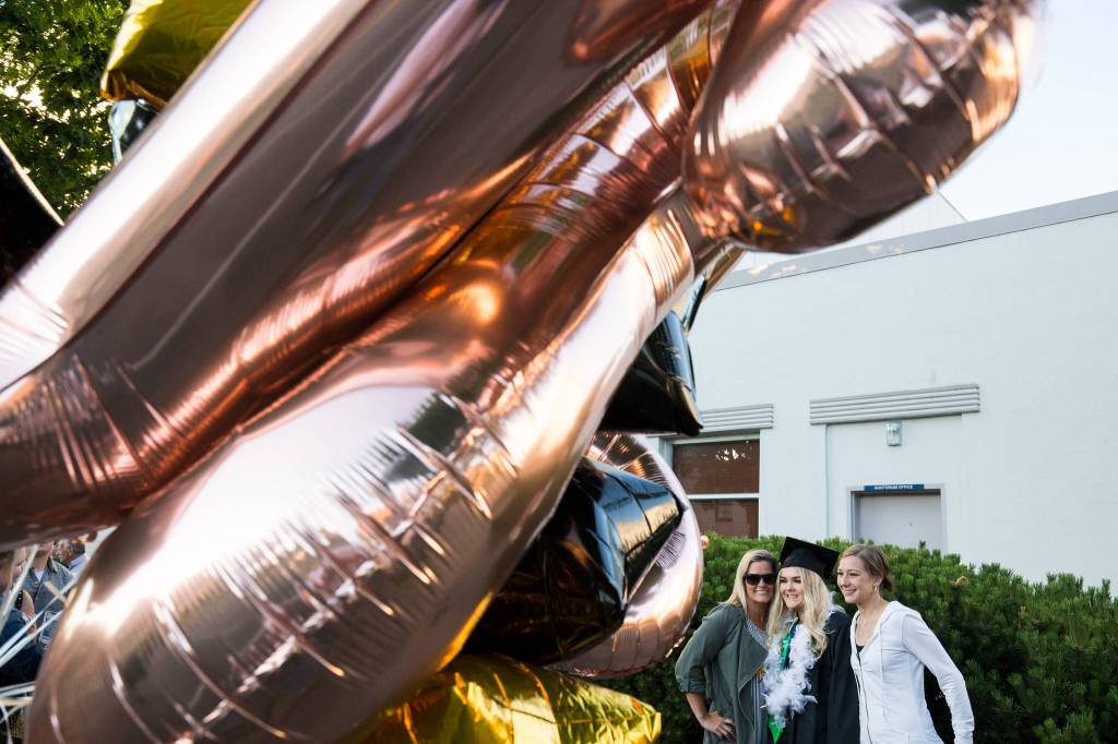 A graduate poses for photos after the Sequoia High School graduation ceremony at the Everett Civic Auditorium on Thursday. (Andy Bronson / The Herald)
