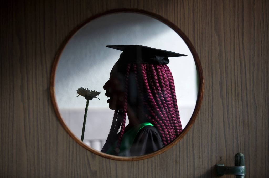 Seen through a door window, Marshawna Green smells a flower as she waits for the Sequoia High School graduation ceremony at the Everett Civic Auditorium on June 14. See the full photo gallery <a href="https://www.heraldnet.com/news/the-sequoia-high-school-commencement-ceremony-in-pictures/" target="_blank">here</a>. (Andy Bronson / The Herald)