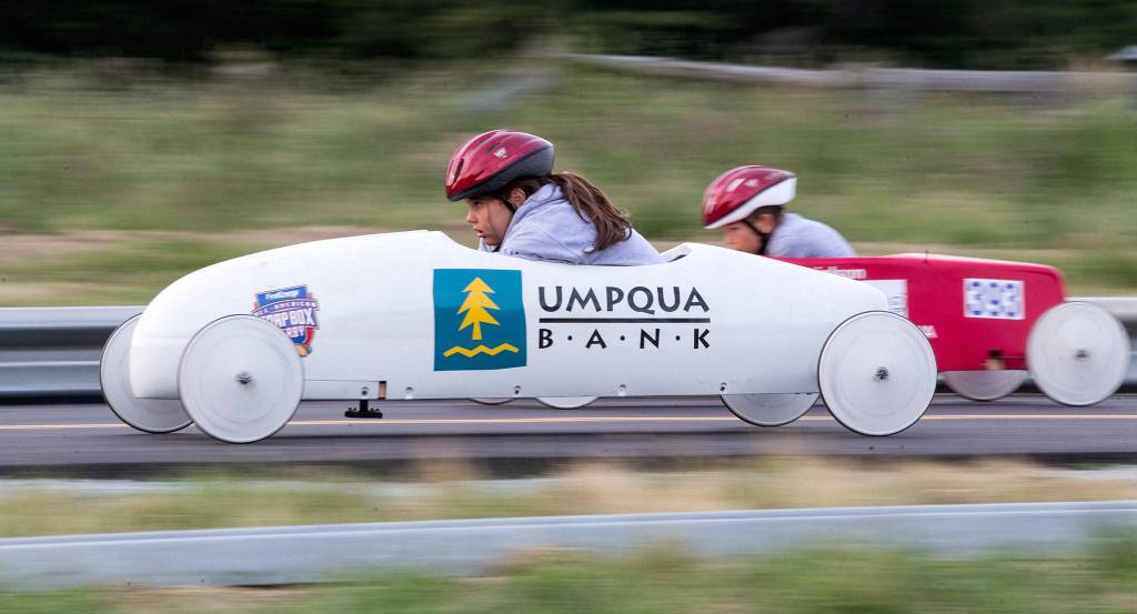 Amelia Allen (left) looks down at the track as she races another driver in unweighted practice soap box derby cars on June 7 in Camano Island. (Andy Bronson / The Herald)