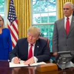 President Donald Trump signs an executive order to keep families together at the border, but says that the zero-tolerance prosecution policy will continue, during an event in the Oval Office of the White House in Washington on Wednesday. Standing behind Trump are Homeland Security Secretary Kirstjen Nielsen (left) and Vice President Mike Pence. (AP Photo/Pablo Martinez Monsivais)