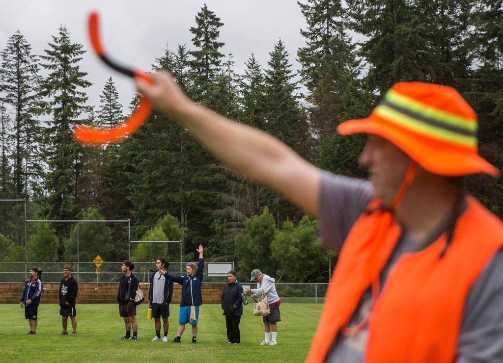 Robert Greer, right, and other boomerang participants help mark the distance of a throw boomerang at Lake Stevens Community Park on Friday, June 22, 2018. (Olivia Vanni / The Herald)