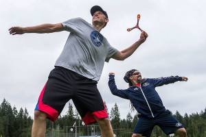 James Stickney, left, and Kenny Barr warm up before long distance boomerang throwing at Lake Stevens Community Park on Friday, June 22, 2018. (Olivia Vanni / The Herald)