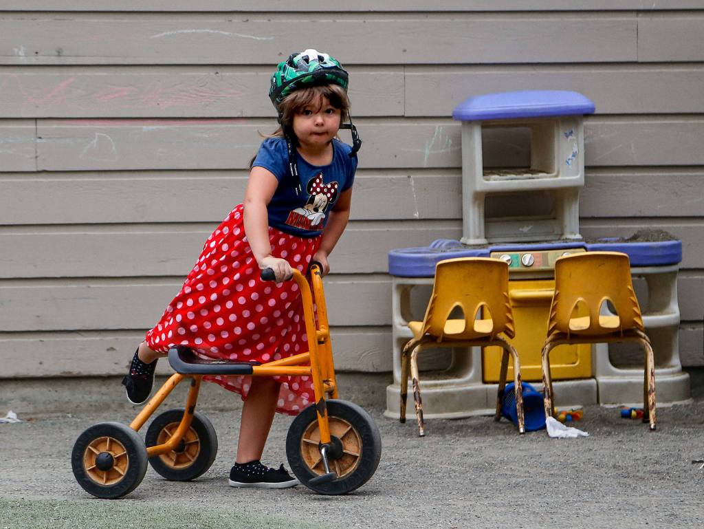 Five-year-old Autumn climbs onto a sturdy tricycle in the playground area at Tomorrows Hope Child Development Center in Everett. (Dan Bates / The Herald)