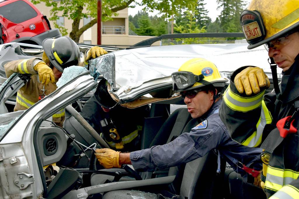 Dave Bronco Erickson, of South County Fire, shows how to turn off an alarm in a mangled car on June 12 at Snohomish Countys first fire academy. (Caleb Hutton / The Herald)