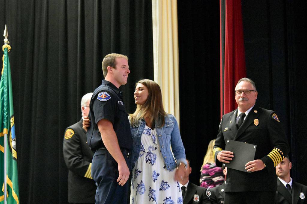 Jamie Dowell looks closely at a pin she placed on her husband, Cory Dowell, at his graduation from Snohomish Countys first fire academy on June 27. (Caleb Hutton / The Herald)