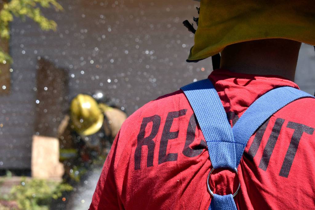 Recruits practice with a firehose during a mock house fire on May 23 as part of Snohomish Countys first fire academy. (Caleb Hutton / The Herald)