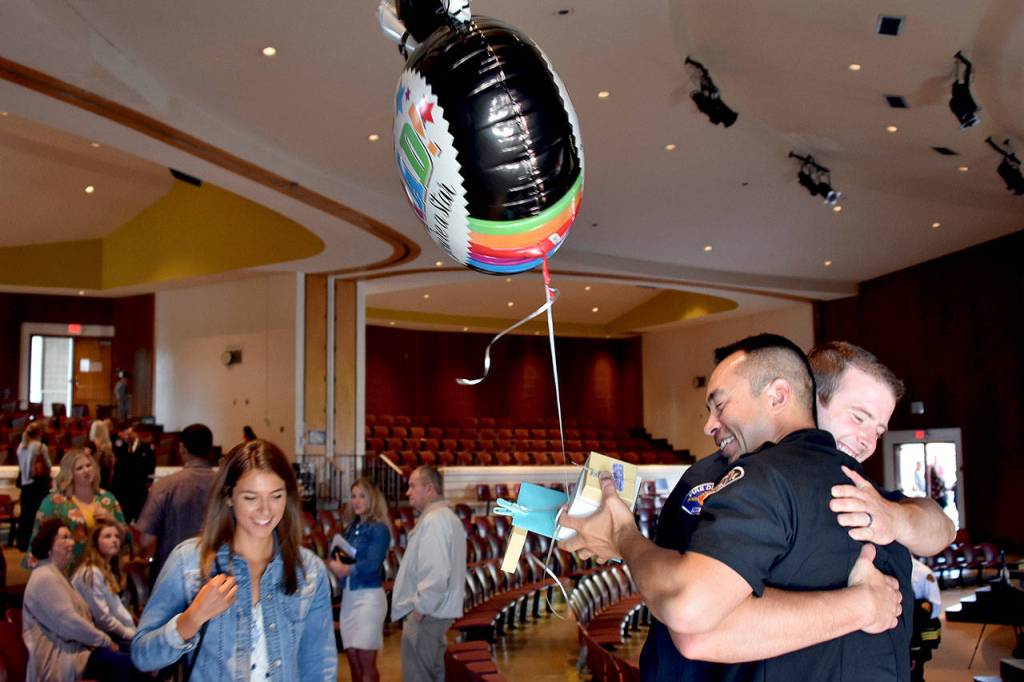 Chau Nguyen (front right) hugs South County Fire recruit Cory Dowell after their graduation from Snohomish Countys first fire academy on June 27. (Caleb Hutton / The Herald)