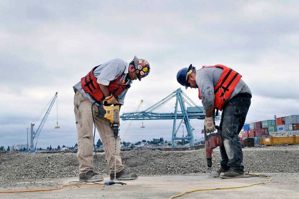 Journeyman pile driver Eugene Bowen (left) and Chris McKinsey, an apprentice pile driver, drill holes during strengthening work on the South Terminal wharf at the south end of the waterfront. (Sue Misao / The Herald)