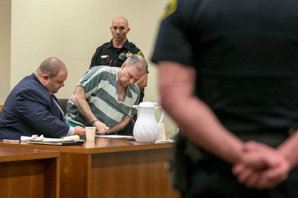 John Reed is fingerprinted by his attorney, Phil Sayles, after being sentenced to life for the 2014 double murder of his neighbors in Oso. (Kevin Clark / The Herald)