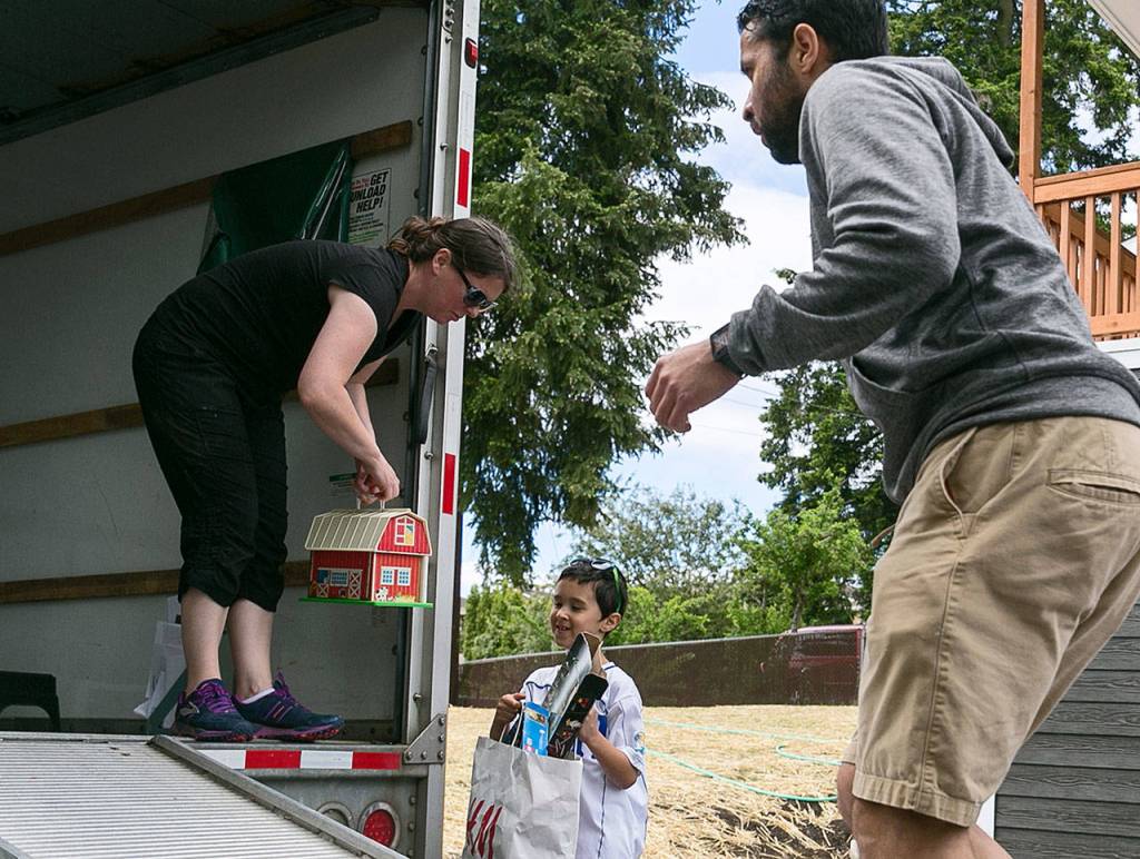 Anna Jiménez hands items to her son, Guillermo David, as her husband, Guillermo Mario, makes his way up the ramp in the moving truck. (Kevin Clark / The Herald)