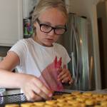 Zoe Bennett, 10, cuts out heart dog treat shapes from her dough in the kitchen on Thursday in Marysville. (Olivia Vanni / The Herald)