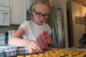 Zoe Bennett, 10, cuts out heart dog treat shapes from her dough in the kitchen on Thursday in Marysville. (Olivia Vanni / The Herald)