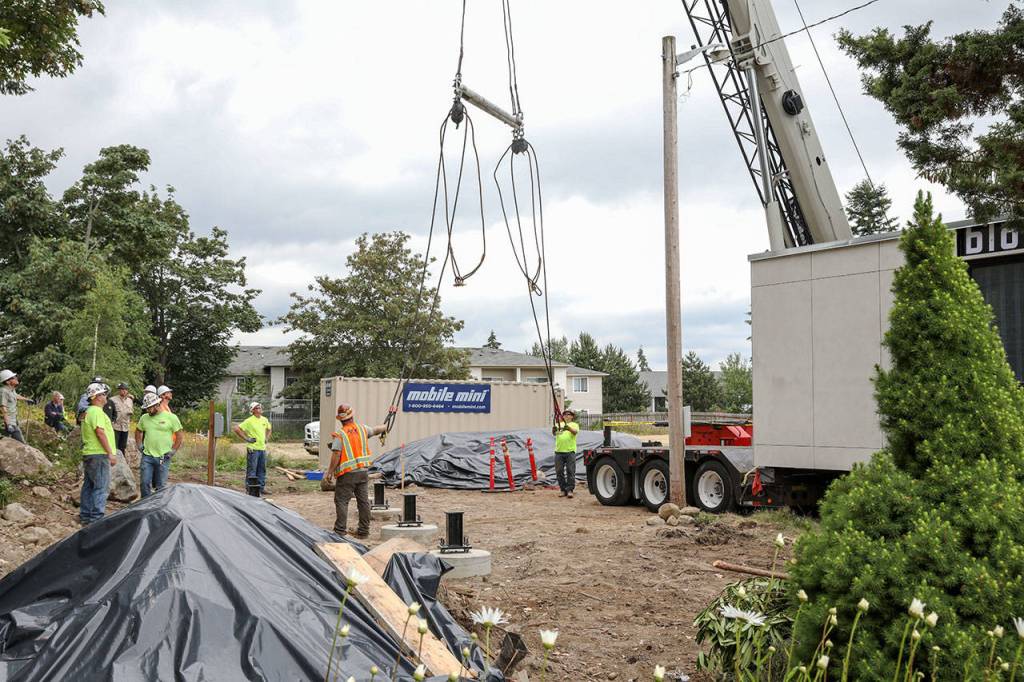 Workers make a plan to place the Blok on its foundation at Edmonds Lutheran Church. (Lizz Giordano / The Herald)