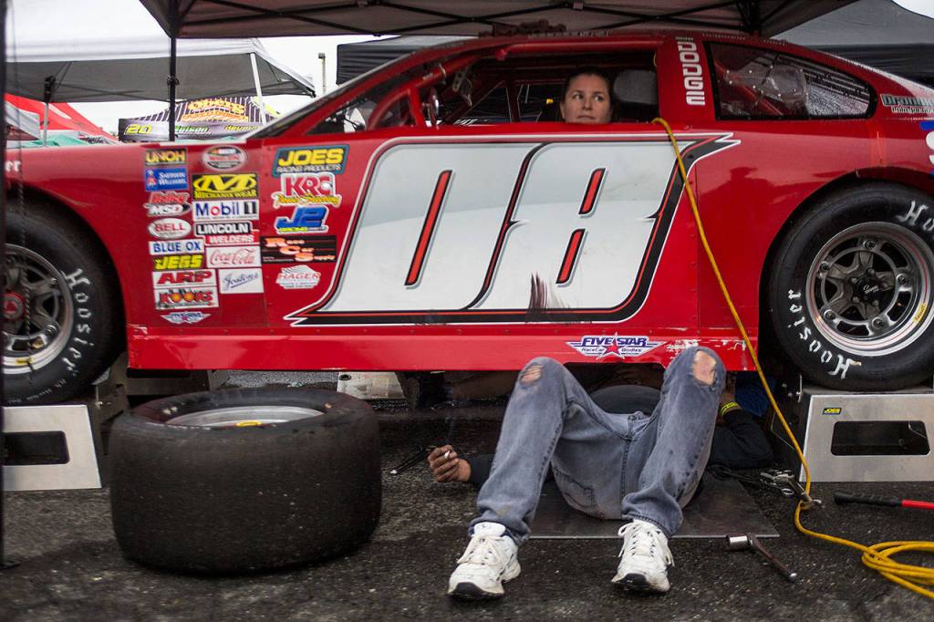 Traci Craig sits in her teams race car as the car is prepped for the 200-lap Super Late Model race at the Summer Showdown at the Evergreen Speedway on Saturday in Monroe. (Olivia Vanni / The Herald)
