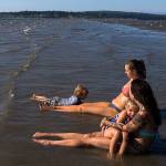 Milissa Simons, right, holds Jet Juliann, 3, while Ashley Elledge, center, watches Lincoln Ballard, 3, swim in the water off of Jetty Island on Thursday, July 5, 2018 in Everett, Wa. (Olivia Vanni / The Herald)