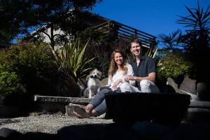Kelsey and Jesse Woodson with their dog, Roger, in their garden in Edmonds. The Woodsons garden will be one of a handful of gardens featured in the Edmonds In Bloom garden tours on July 15. (Olivia Vanni / The Herald)