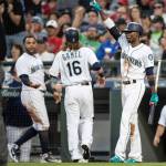 The Mariners Dee Gordon gestures to second base as Nelson Cruz congratulates Ben Gamel, who scored on a double by Guillermo Heredia during the fifth inning of a game July 5, 2018, in Seattle. (AP Photo/Stephen Brashear)