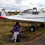 Laura Junjek reads under the wing of a 1947 North American Navion at the 50th annual Arlington Fly-In at the Arlington Airport on Saturday. Laura and her husband Bill flew in from Renton. (Andy Bronson / The Herald)