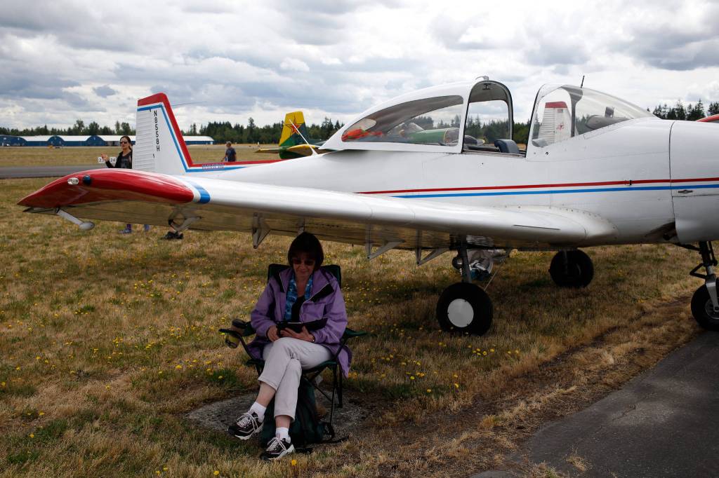 Laura Junjek reads under the wing of a 1947 North American Navion at the 50th annual Arlington Fly-In at the Arlington Airport on Saturday. Laura and her husband Bill flew in from Renton. (Andy Bronson / The Herald)