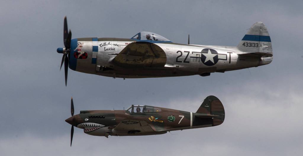 A P-47 Thunderbolt (top) passes a P-40 Tomahawk during maneuvers at the 50th annual Arlington Fly-In at the Arlington Airport on Saturday. (Andy Bronson / The Herald)