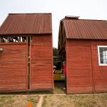 Volunteer Daniel Oliver pushes as Mike Bird (center) yells out directions as one section of a red barn in moved into position at the Arlington Airport, in preparation for the Arlington Fly-In, on June 27. The barn is the centerpiece of a historic airplane exhibit during the airshow event. (Andy Bronson / The Herald)